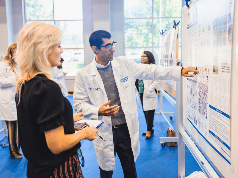 Dr. Jill Clayton listens as Dr. Babak Alibayov presents his research. Lindsay McMurtray/ UMMC Communications